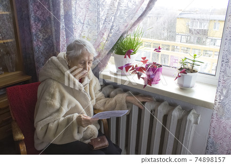 Woman holding cash in front of heating radiator. Payment for heating in winter. Selective focus. 74898157