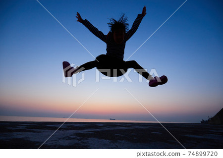 大海的美麗日落美景,與一個孩子在沙灘上大力跳躍 大海的美麗日落美景,與一個孩子在沙灘上大力跳躍 74899720