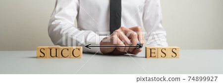 Businessman connecting two sides of wooden blocks to spell the word Success Businessman connecting two sides of wooden blocks to spell the word Success 74899927