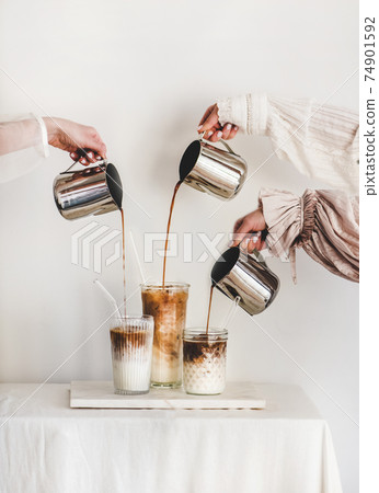 Female hands pouring coffee to glasses with milk 74901592