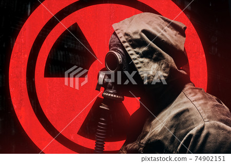 Stalker warrior in protective soviet gas mask standing on glowing red radiation sign. 74902151