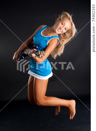 Attractive girl with guitar in jump Attractive girl with guitar in jump 74902383