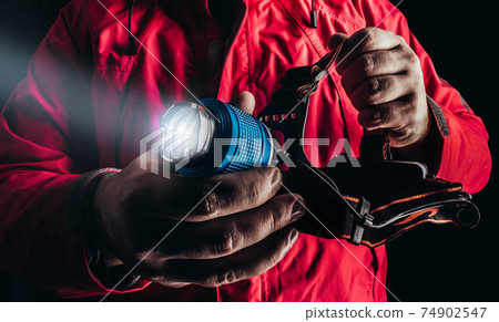 Close-up product photo of hiker man in red travel camping jacket holding shining head flashlight. Close-up product photo of hiker man in red travel camping jacket holding shining head flashlight. 74902547