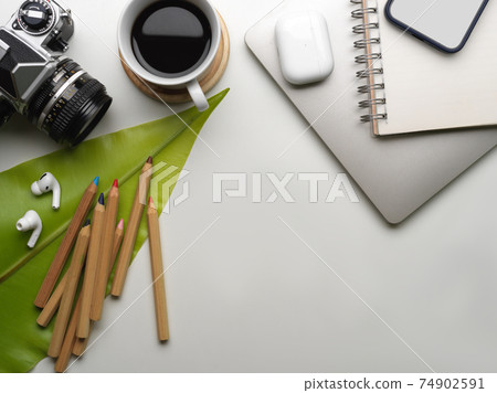 Workspace with camera, smartphone, coffee cup, supplies, copy space and leaf decorated on the table Workspace with camera, smartphone, coffee cup, supplies, copy space and leaf decorated on the table 74902591