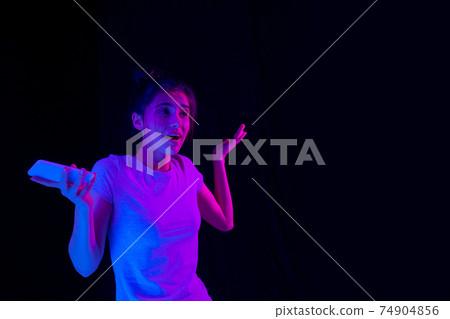 Portrait of Caucasian beautiful girl over dark background in neon light. Portrait of Caucasian beautiful girl over dark background in neon light. 74904856