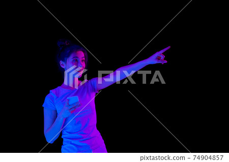 Portrait of Caucasian beautiful girl over dark background in neon light. 74904857