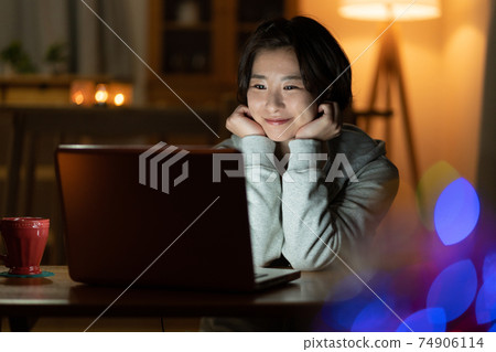 看一台計算機的少婦在客廳在晚上 看一台計算機的少婦在客廳在晚上 74906114