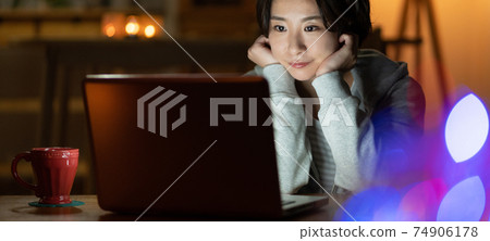 Young woman looking at a computer in the living room at night Banner size Young woman looking at a computer in the living room at night Banner size 74906178