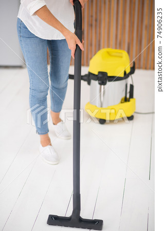 Female hands lightly vacuuming white floor 74906235