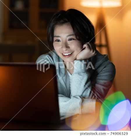 Young woman looking at a computer in the living room at night Square Young woman looking at a computer in the living room at night Square 74906329