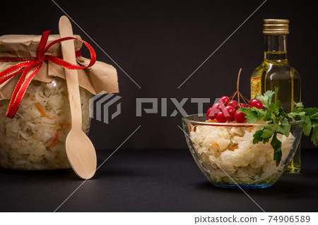 Fermented cabbage with herbs and spices in glass bowl and jar on the black background 74906589