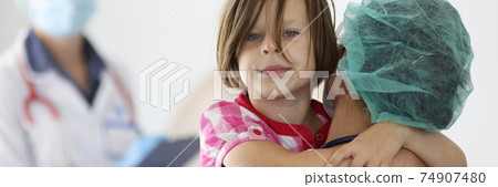 Doctor holds girl in his arms in medical office 74907480