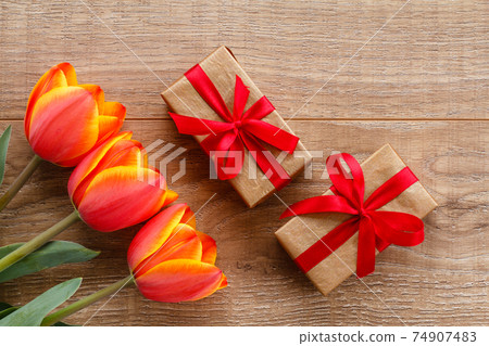 Gift boxes with red ribbons on wooden boards. Gift boxes with red ribbons on wooden boards. 74907483