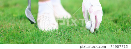 Golfer fixes golf ball and holds golf club in his hand. Golfer fixes golf ball and holds golf club in his hand. 74907715