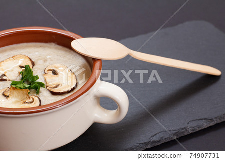 Cream soup with mushrooms in porcelain bowl on black background. 74907731