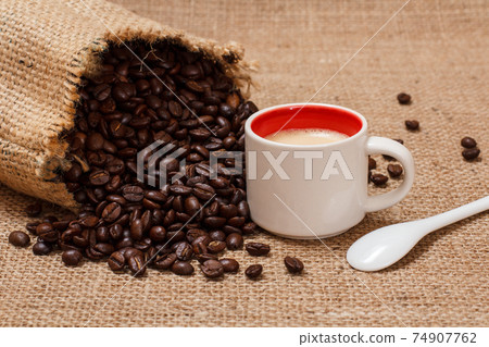 Cup of coffee and roasted coffee beans in a canvas sack. Cup of coffee and roasted coffee beans in a canvas sack. 74907762