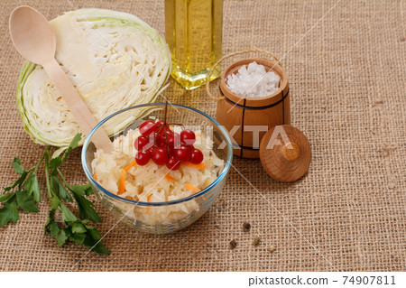 Fermented cabbage with herbs and spices in glass bowl and fresh cabbage on the background. 74907811