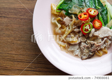 Fried Wide Rice Noodles with Pig in Gravy Sauce on the Wood Table 74908081