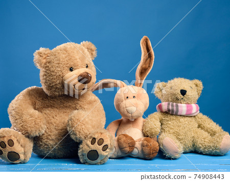 brown teddy bear and cute rabbit sit on a blue background brown teddy bear and cute rabbit sit on a blue background 74908443