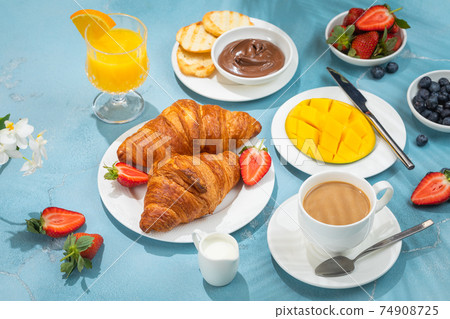 Luxury sunny continental breakfast on blue concrete background table with tropical plants shadows 74908725