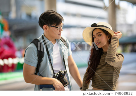 Asian couple enjoy travelling and walking on the street in city. 74908932