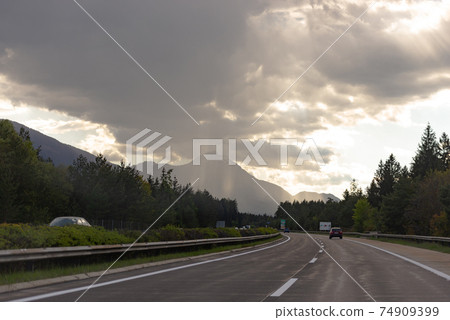 Roads Of Austria. Austrian highway with beautiful views. Wet road after rain. Photo from the car. 74909399