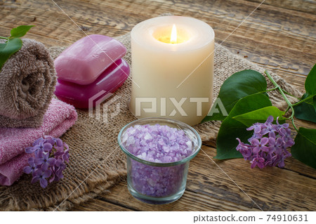 Towel, soap, candle and lilac flowers on wooden background. 74910631