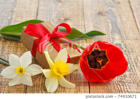 Flowers of daffodils and tulip with gift box on wooden boards Flowers of daffodils and tulip with gift box on wooden boards 74910671