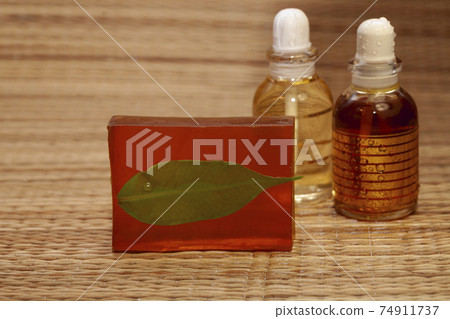 bar of natural handmade soap from indian and bottle with aroma oil natural ingredients with green leaf. 74911737