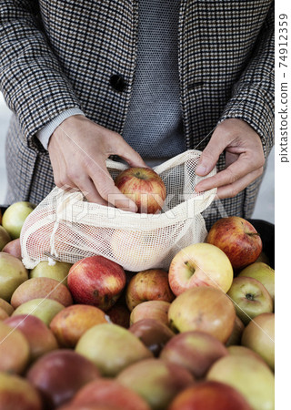 man uses a reusable mesh bag at the greengrocer 74912359