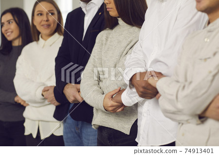 Team of happy young company employees standing together and holding hands, supporting each other Team of happy young company employees standing together and holding hands, supporting each other 74913401