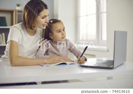 Small positive girl and her mother drawing or learning alphabet and writing during online lesson Small positive girl and her mother drawing or learning alphabet and writing during online lesson 74913610