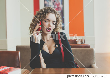 Young beautiful woman using smartphone while sitting at cafeteria. 74913756