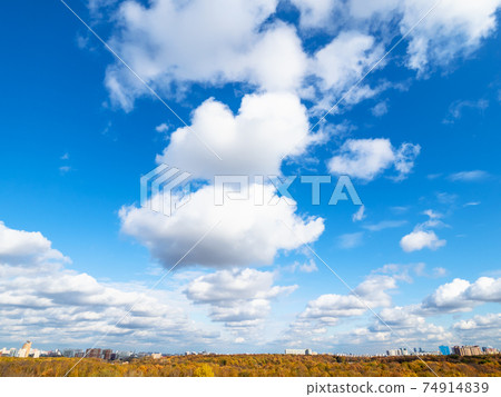 wedge of clouds in blue sky over yellow city park 74914839