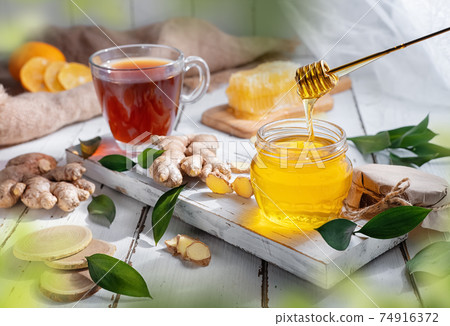 Still-life with honey and fresh tea in a transparent tea cup Still-life with honey and fresh tea in a transparent tea cup 74916372