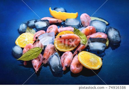 Raw shrimp prawns with ice and lemon on blue background 74916386
