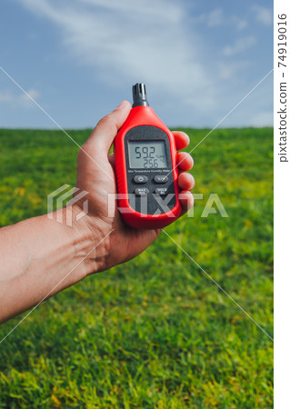 portable thermometer in hand measuring outdoor air temperature and humidity 74919016