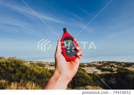 portable thermometer in hand measuring outdoor air temperature and humidity 74919032