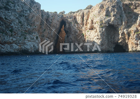 Calm sea waves washing big rocky cliff. 74919328