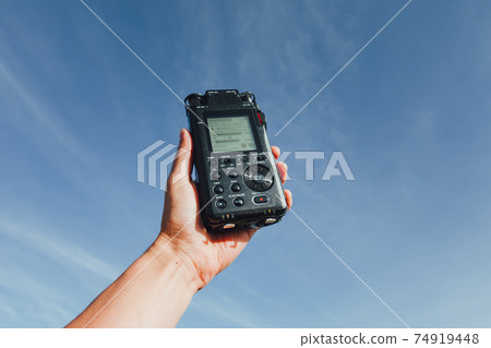 portable audio recorder in hand recording ambient sounds of nature 74919448