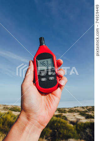 portable thermometer in hand measuring outdoor air temperature and humidity 74919449