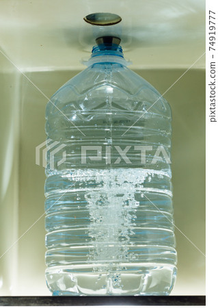 pouring water in the bottle with water dispenser 74919777