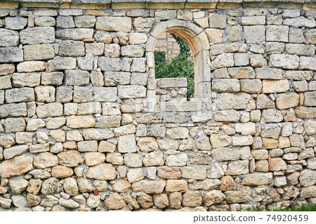 stone wall of an ancient building with a semicircular window, beyond which other ruins are visible stone wall of an ancient building with a semicircular window, beyond which other ruins are visible 74920459
