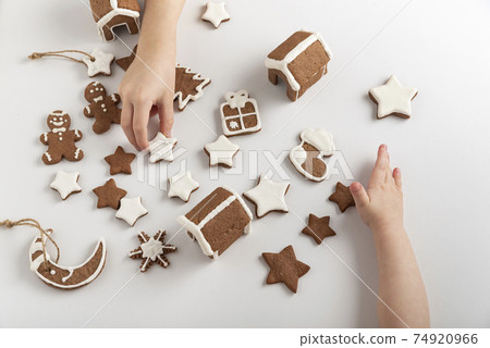 Children are getting ready for Christmas. Sugar glazed gingerbread cookies in children's hands. Top view Children are getting ready for Christmas. Sugar glazed gingerbread cookies in children's hands. Top view 74920966