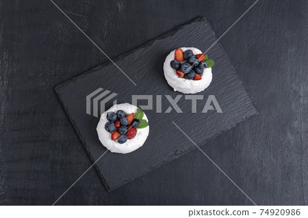 Meringue cake with fresh berries. Berry dessert on black background, top view. 74920986