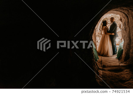 couple bride and groom in wedding dress stand in a hole in rock 74921534