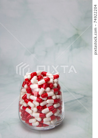 Filled glass with capsules pills for medication.drugs or vitamin,assorted pharmaceutical medicine tablets, in jar, health,business,medication concept with copy space 74922204