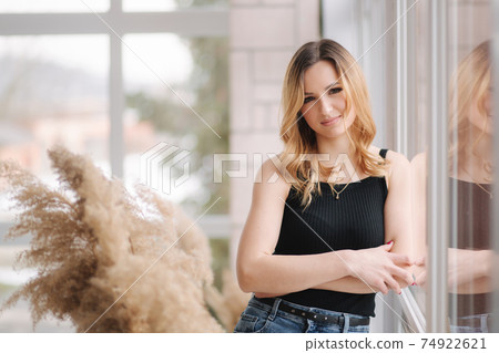Young attractive woman in studio sit near the window. Female in denim. Home style Young attractive woman in studio sit near the window. Female in denim. Home style 74922621