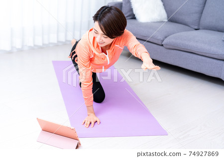 Middle-aged woman doing online yoga at home Middle-aged woman doing online yoga at home 74927869