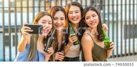 Happiness Asian Girl Friend Group taking a selfie while celebrating and dancing together with her beer bottle at sunset time on rooftop, hens night, holiday, or yearly anniversary party concept Happiness Asian Girl Friend Group taking a selfie while celebrating and dancing together with her beer bottle at sunset time on rooftop, hens night, holiday, or yearly anniversary party concept 74930033